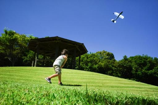 <素材>夏の公園で飛行機を飛ばす男の子 <素材>夏の公園で飛行機を飛ばす男の子 子供,青空,飛行機の写真素材