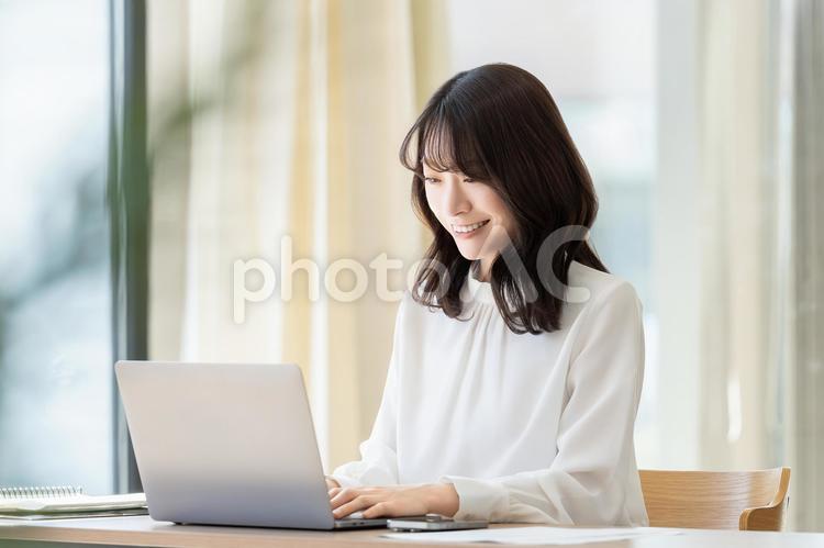 デスクワークをする笑顔のビジネスウーマン 女性,ビジネス,パソコンの写真素材