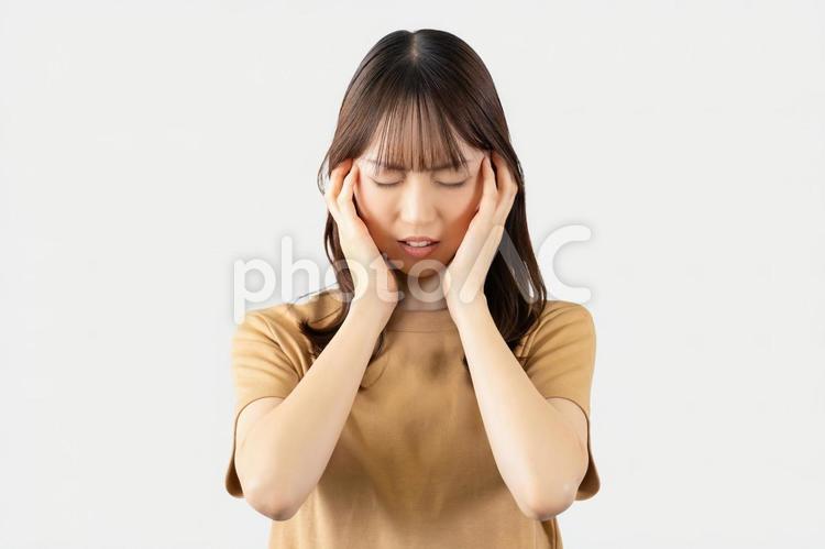 頭を押さえて悩む女性 女性,悩む,困るの写真素材