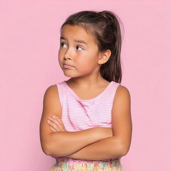 ピンクの背景に立つ、拗ねた様子の幼い少女 ピンクの背景に立つ、拗ねた様子の幼い少女の写真