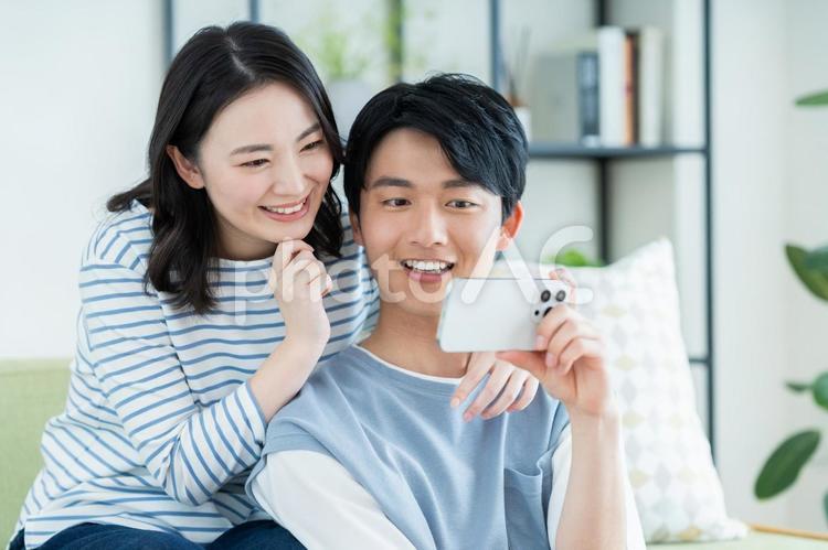 スマホで動画を見る若い夫婦 スマホ,夫婦,動画の写真素材