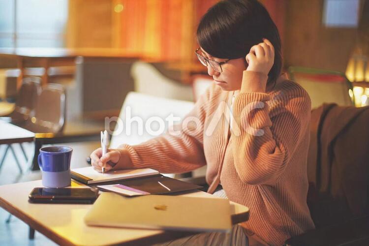 カフェでメモをとるメガネをかけた女性 幸福,ファッション,ノートの写真素材