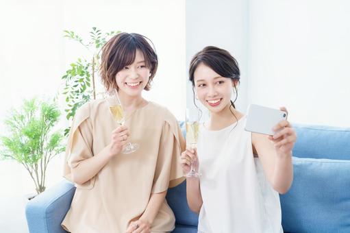 Two women taking a picture of a champagne glass in their hands, JPG Two women taking a picture of a champagne glass in their hands, woman will be, home party, commemorative photo, JPG