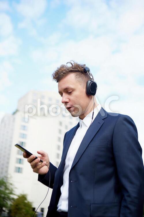 スマホで音楽を聞くビジネスマン1 ビジネスマン,男性,外国人の写真素材