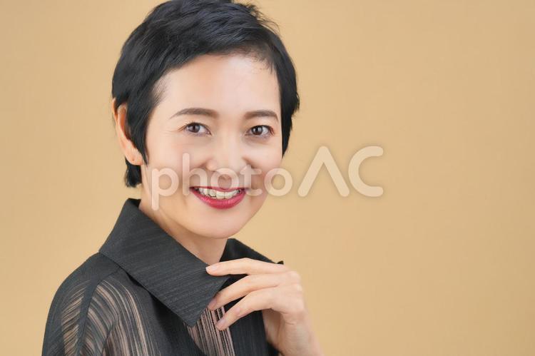 笑顔でカメラ目線のショートカットの女性（ベージュ背景） 女性,日本人,50代の写真素材
