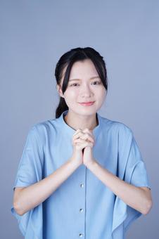 両手を胸の前に組んだ青い服の女性 女性,手を組む,微笑むの写真素材