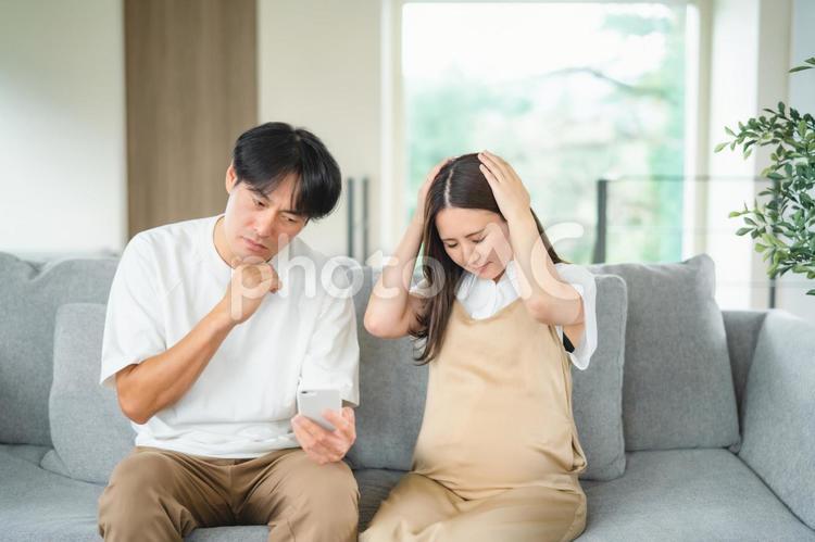 スマホを見る妊婦と男性（悩む） 妊婦,妊娠,夫婦の写真素材