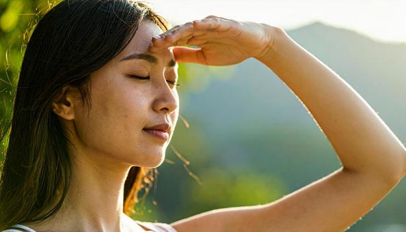 太陽の光をまぶしそうに浴びる女性 太陽の光をまぶしそうに浴びる女性の写真
