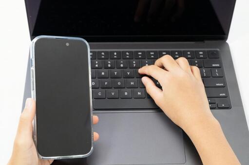 ノートPCとスマートフォンを操作する手元 スマートフォン,ノートパソコン,手の写真素材