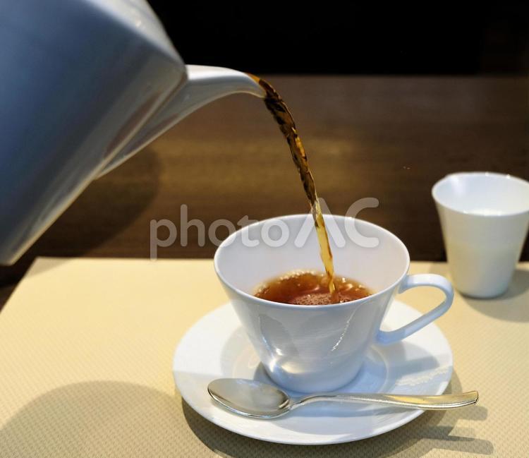 明るいレストランでホテルスタッフに注いでもらっている紅茶 紅茶,注がれる,注ぐの写真素材