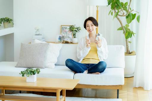 部屋でスマホを使うミドル女性 部屋でスマホを使うミドル女性 スマホ,笑顔,女性の写真素材