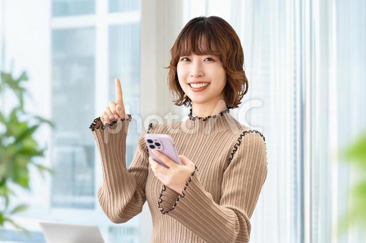 スマホを持って案内をする笑顔の女性 女性,人物,スマホの写真素材