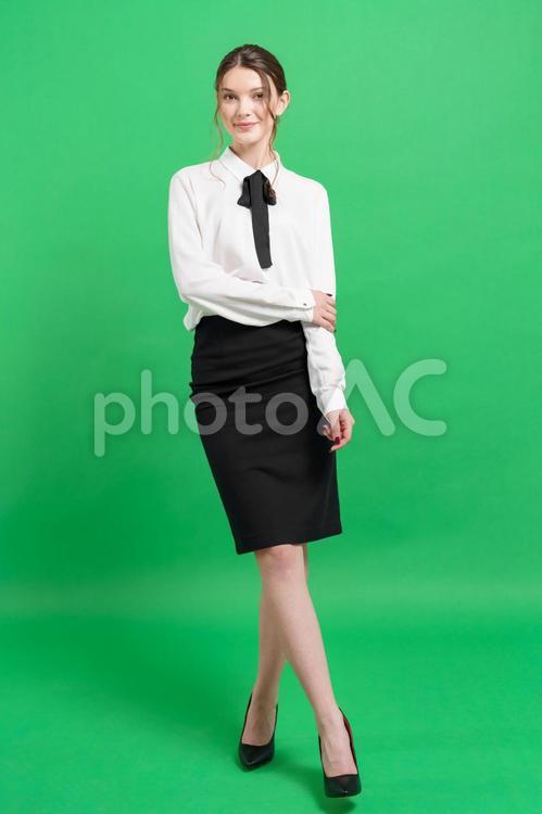 カメラ目線で左腕を掴む女性（緑背景） 女性,立つ,ポーズの写真素材