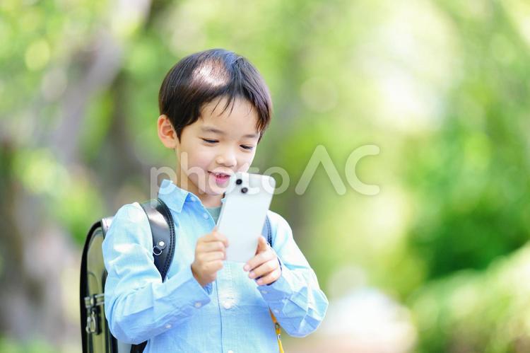スマホを見て笑うランドセルの男の子 男の子,スマートフォン,持つの写真素材