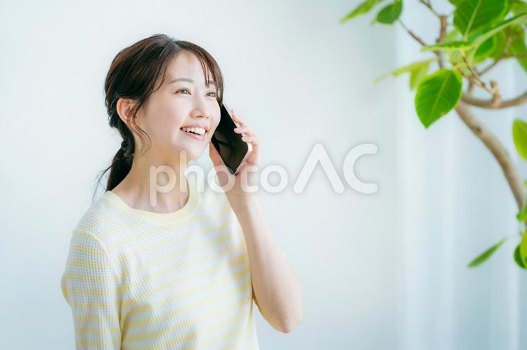 部屋でスマホを操作する女性 スマホ,笑顔,女性の写真素材