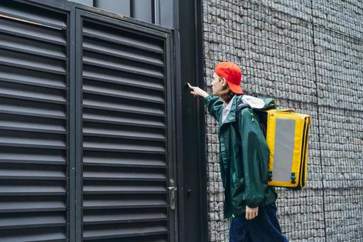 インターホンを押すフードデリバリーの男性 配達,デリバリー,配送の写真素材