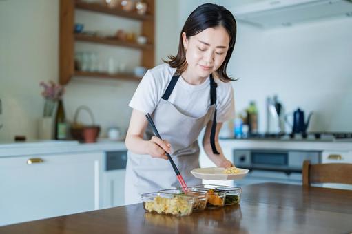 作り置きしたお惣菜をお皿に盛る女性  家事,料理,作り置きの写真素材