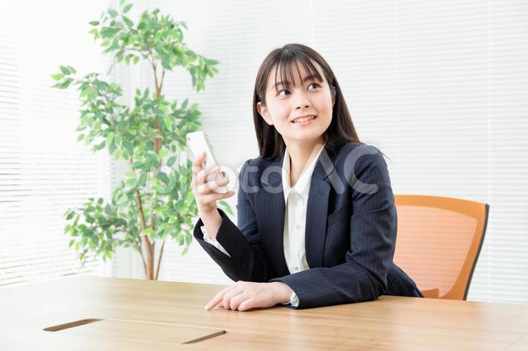 オフィスでスマホを動かす女性社員3 スーツ,企業,テーブルの写真素材