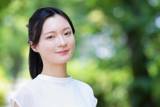 白いノースリーブワンピースの女性が微笑むの写真