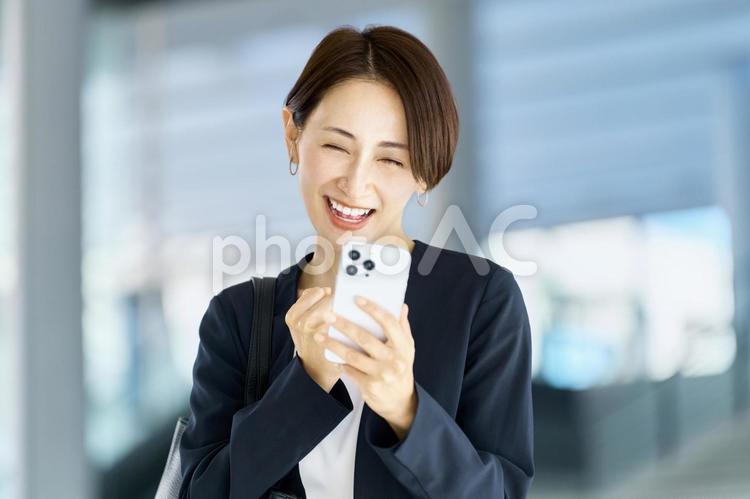スマホを見るビジネスウーマン　笑顔 ビジネスウーマン,スマホ,通勤の写真素材