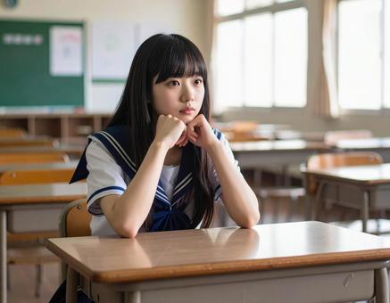 1人で教室で悩むセーラー服の女子学生の写真