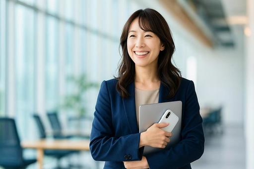 ノートパソコンとスマホを手に持つ若い女性 ノートパソコンとスマホを手に持つ若い女性の写真