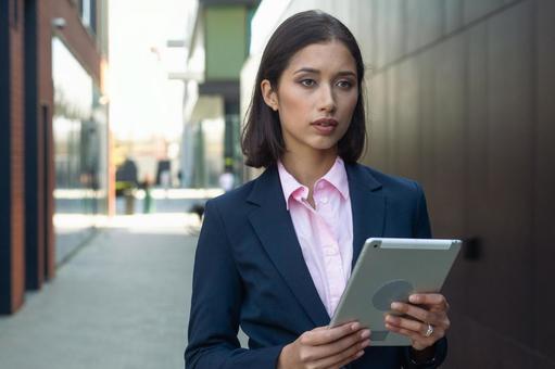 街なかでタブレットを持って立っているビジネスウーマン ビジネスウーマン,ビジネス,女性の写真素材