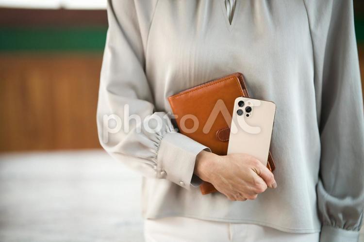 手帳と携帯を抱える女性の手元 手元,女性,手帳の写真素材