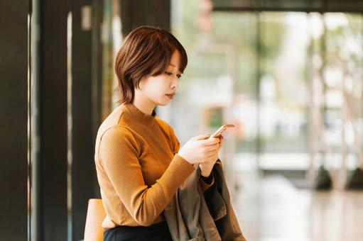 スマホを使う秋服の女性・ビジネスウーマン スマホを使う秋服の女性・ビジネスウーマン 女性,スマホ,秋の写真素材
