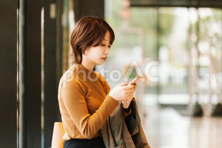 スマホを使う秋服の女性・ビジネスウーマン 女性,スマホ,秋の写真素材