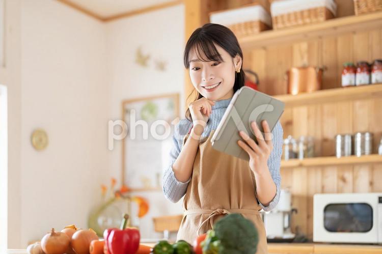 キッチンでタブレットを使う笑顔の女性 女性,キッチン,料理の写真素材