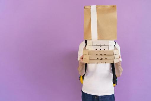 ピザの箱と紙袋を重ねて持つフードデリバリーの男性（紫背景） 配達,デリバリー,配送の写真素材