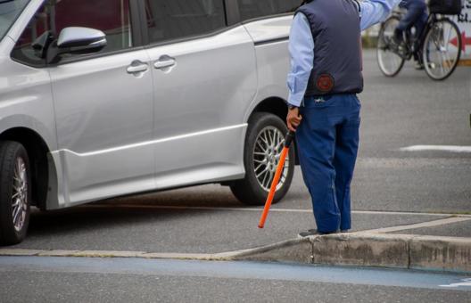 駐車場の出口で自動車を誘導する誘導員 駐車場の出口で自動車を誘導する誘導員 ファン付きウェア,空調服,電動ファン内蔵上着の写真素材