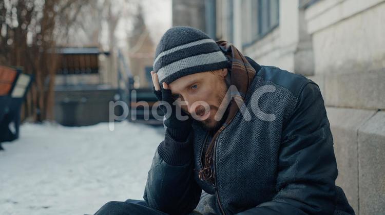 頭を抱えて考える男性のホームレス 男性,ニット帽,人物の写真素材