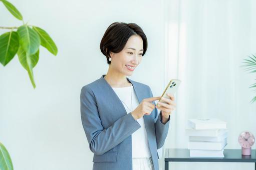 スマホを操作するビジネスウーマン スマホ,笑顔,ビジネスウーマンの写真素材