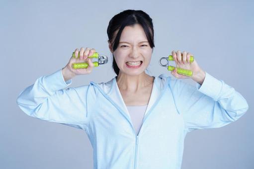 水色の服の女性が健康器具を顔の横に持つ 女性,ハンドグリップ,握るの写真素材