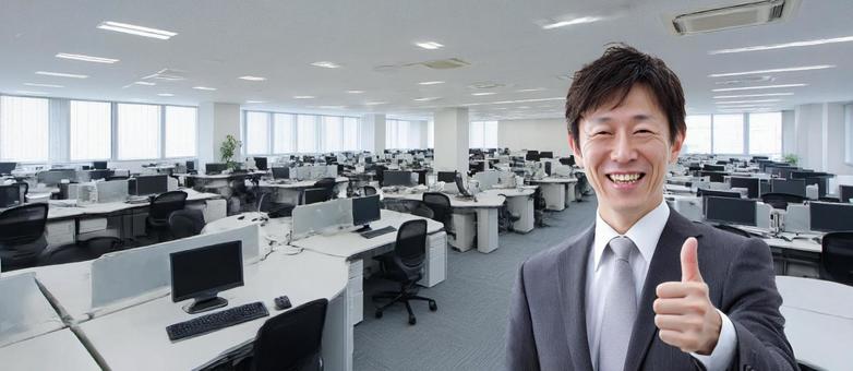 グッドサインを出すスーツの男性と職場 グッドサインを出すスーツの男性と職場の写真