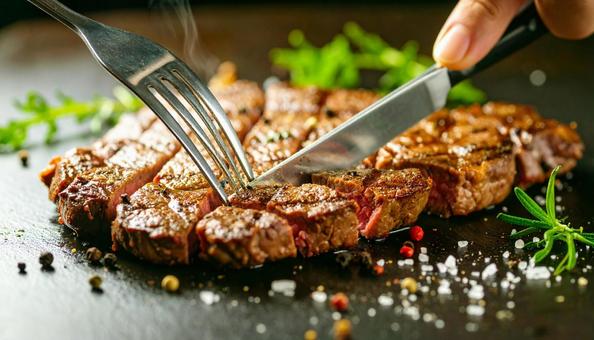 鉄板焼きのステーキをナイフで切る 鉄板焼きのステーキをナイフで切るの写真