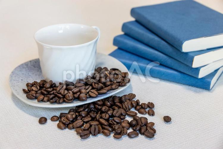 白いカップとコーヒー豆、積まれた青い本 カップ,コーヒー,豆の写真素材