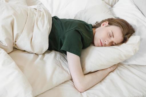 ベッドでうつ伏せで寝る若い男性 男性,外国人,欧米人の写真素材