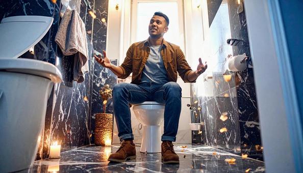 男子トイレで暇つぶしをする男性の写真