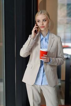 コーヒー片手に電話しているビジネスウーマン ビジネスウーマン,ビジネス,女性の写真素材