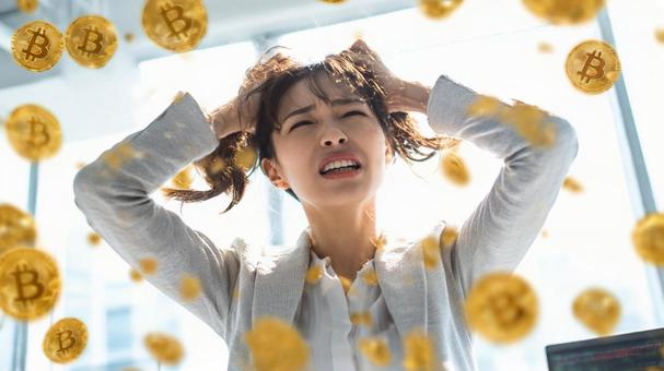 頭を抱える女性とビットコインのイメージ3の写真