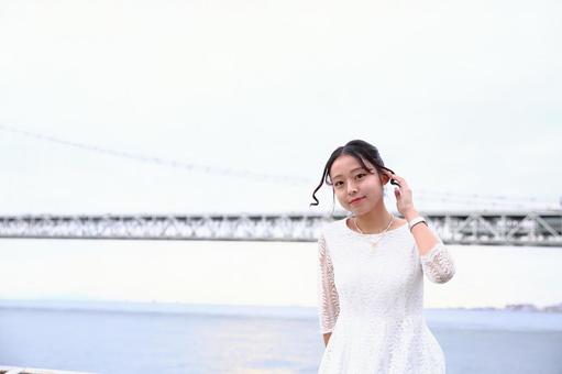 海沿いの堤防でカメラ目線の女性 女性,座る,海岸の写真素材