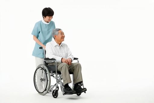 車椅子の高齢男性を優しく支える介護士の写真
