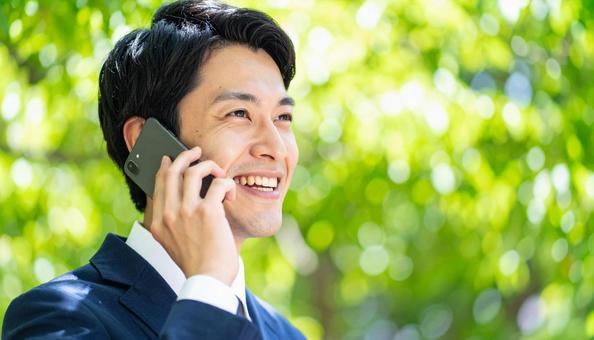 携帯電話で会話する若いビジネスマン 携帯電話で会話する若いビジネスマンの写真