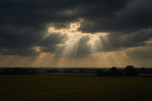厚い雲の隙間から射す光、天使の梯子の写真