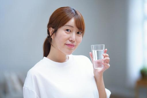 カメラ目線で水のコップを持つ女性 女性,水,飲み物の写真素材