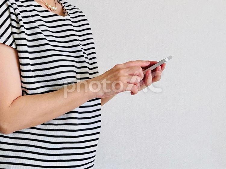 スマホを操作するボーダー柄の服を着た女性 スマホ,女性,操作の写真素材