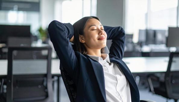 オフィスで目を閉じリラックスする女性社員 オフィスで目を閉じリラックスする女性社員の写真